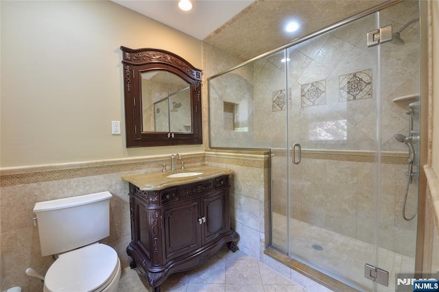 full bathroom with tile walls, toilet, a shower stall, a wainscoted wall, and vanity