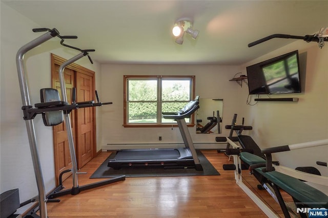 exercise room with wood finished floors and baseboard heating