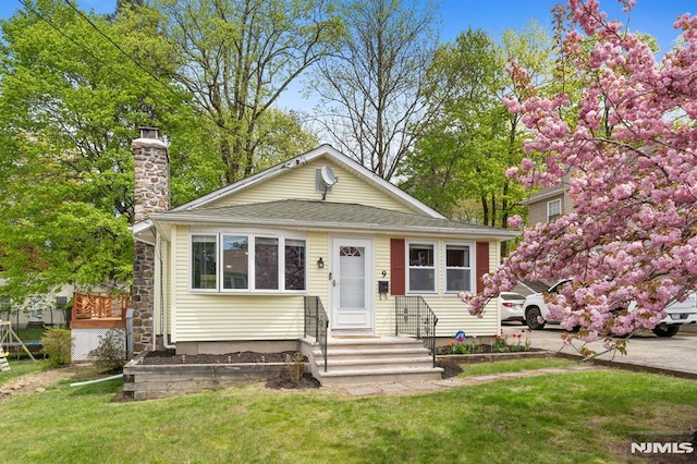 bungalow featuring a chimney and a front yard