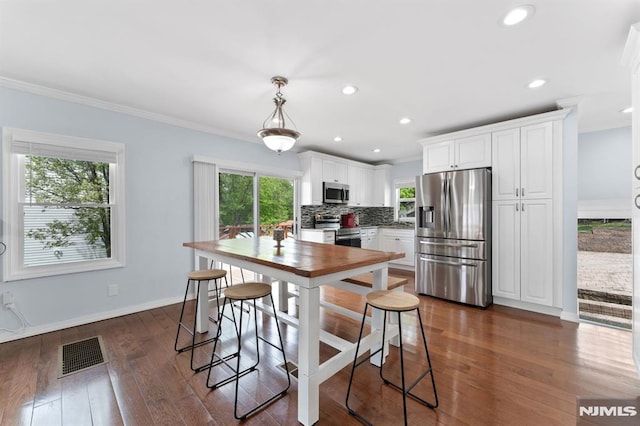 kitchen with dark wood-style flooring, visible vents, white cabinetry, tasteful backsplash, and appliances with stainless steel finishes