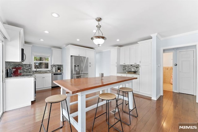 kitchen with crown molding, white cabinets, and appliances with stainless steel finishes