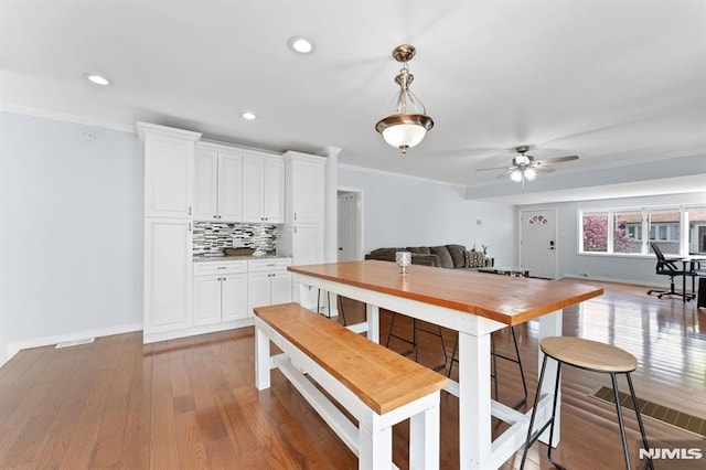 dining space featuring crown molding, baseboards, hardwood / wood-style floors, and recessed lighting