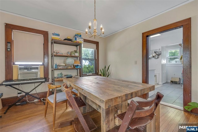 dining space featuring a chandelier, wood-type flooring, healthy amount of natural light, cooling unit, and ornamental molding