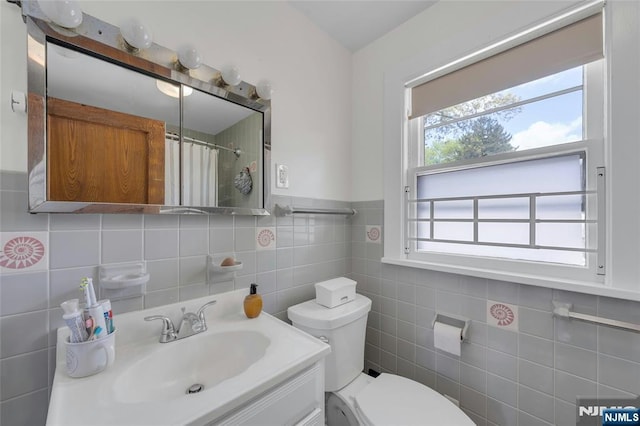 full bath with tile walls, toilet, vanity, and a shower with curtain