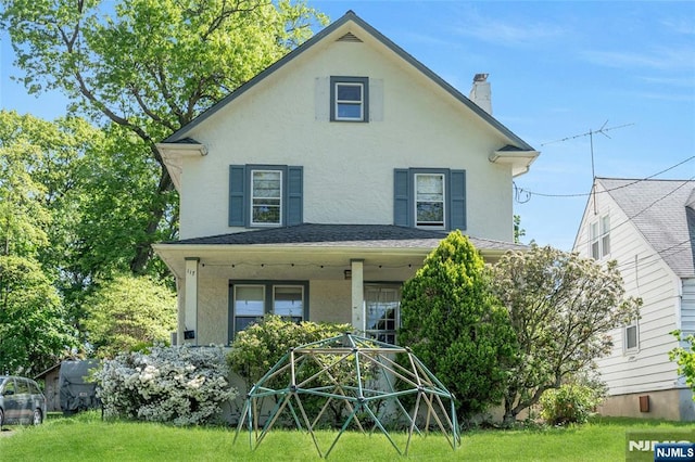 back of house featuring stucco siding, a chimney, covered porch, and a lawn