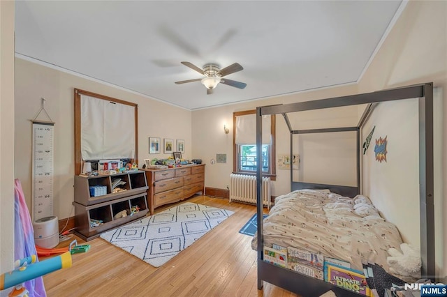 bedroom featuring radiator heating unit, wood finished floors, crown molding, baseboards, and ceiling fan