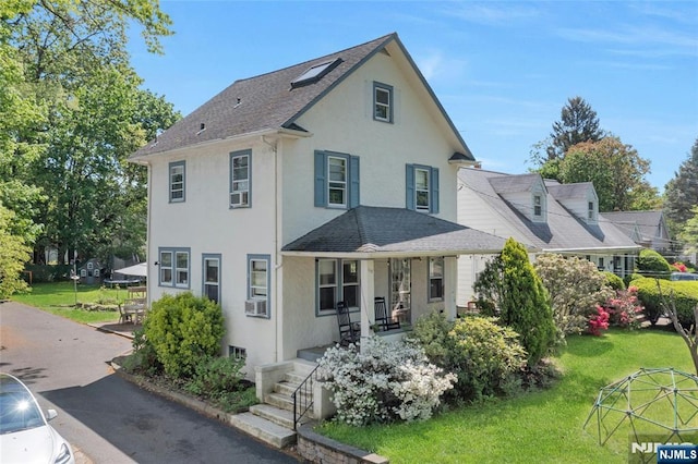 back of house featuring a porch, stucco siding, a shingled roof, and a lawn