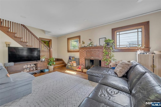 living room with stairway, wood finished floors, and a brick fireplace