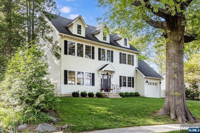 colonial house with an attached garage, roof with shingles, and a front yard