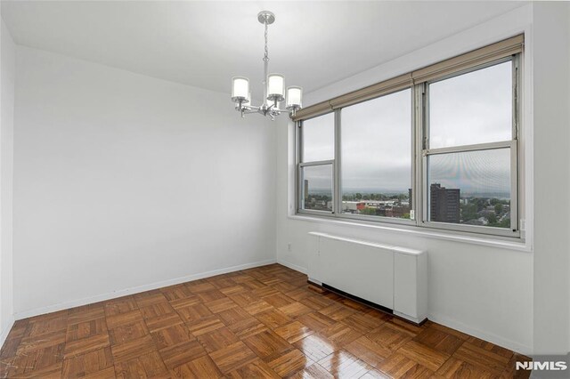empty room featuring a chandelier, baseboards, and radiator