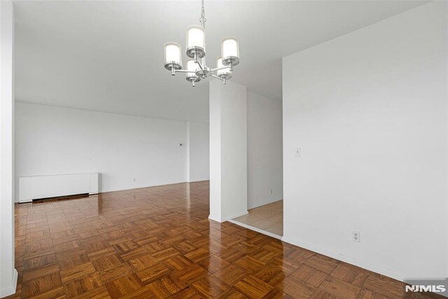 spare room with a chandelier and baseboards