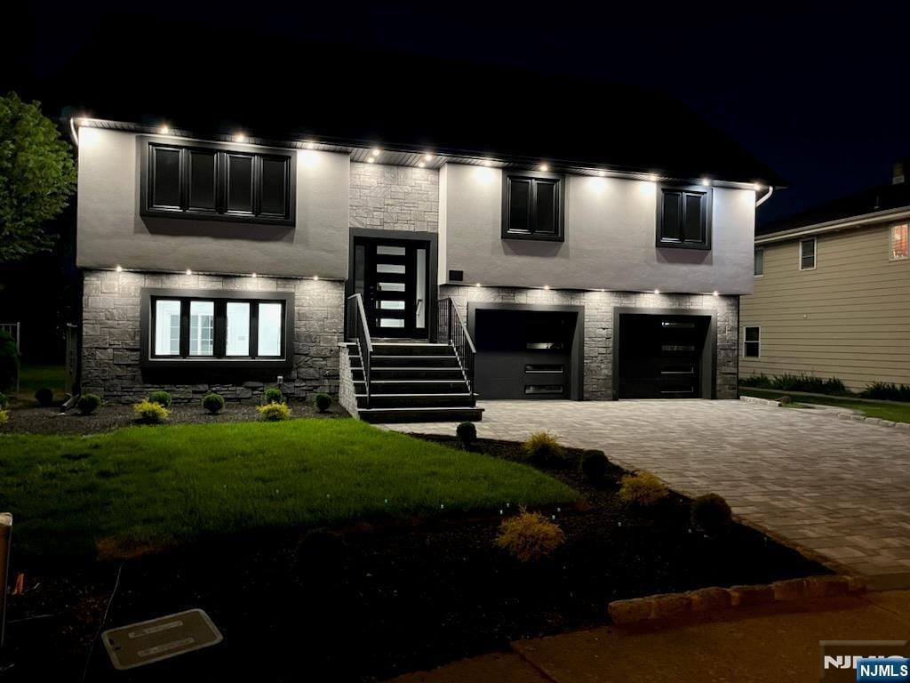 view of front of house with a lawn, decorative driveway, stone siding, and a garage
