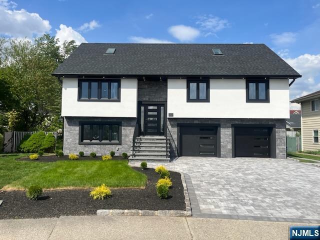 raised ranch featuring fence, a garage, stucco siding, a front yard, and decorative driveway