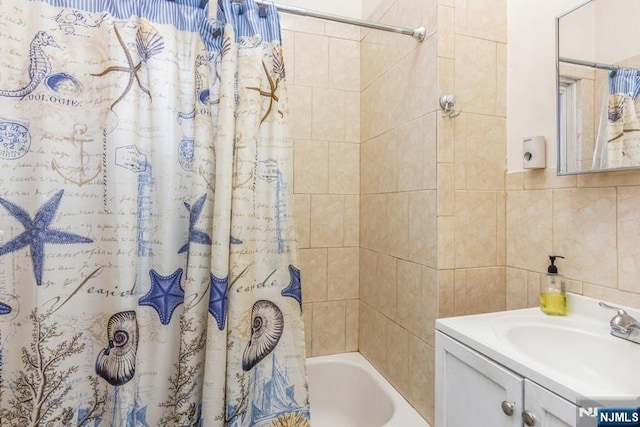 bathroom featuring vanity, shower / bath combo with shower curtain, and tile walls