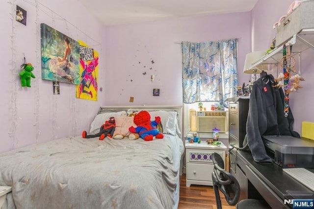 bedroom with cooling unit and wood finished floors