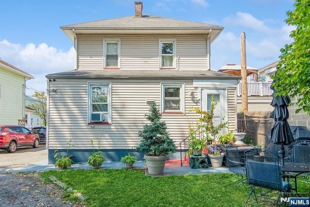 back of property with fence, a chimney, and a yard