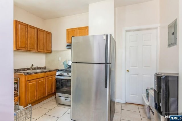 kitchen featuring a sink, brown cabinetry, stainless steel appliances, under cabinet range hood, and electric panel