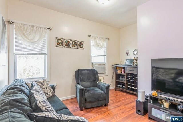 living area featuring baseboards, wood finished floors, and cooling unit
