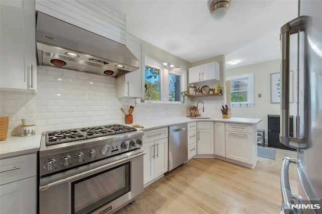 400 Prospect Ave, Oradell, NJ 07649 - kitchen with appliances with stainless steel finishes, exhaust hood, a sink, light countertops, and light wood-type flooring