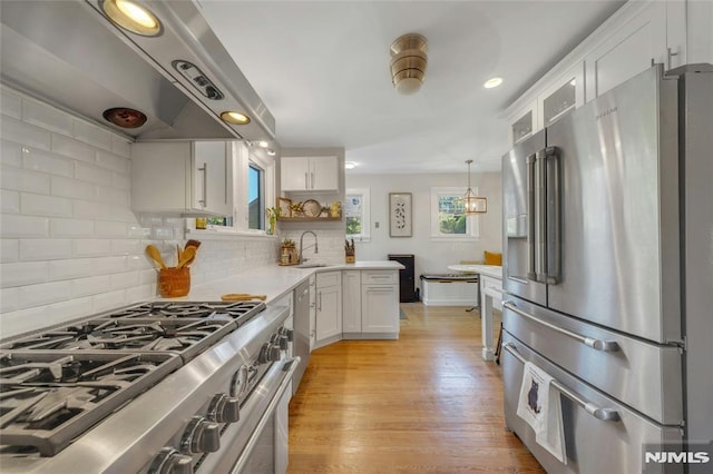 400 Prospect Ave, Oradell, NJ 07649 - kitchen with stainless steel appliances, exhaust hood, white cabinets, light countertops, and decorative backsplash