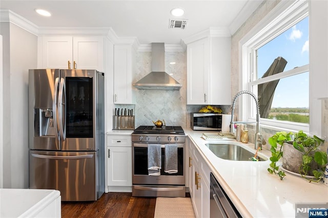 kitchen with stainless steel appliances, visible vents, a sink, wall chimney exhaust hood, and light countertops