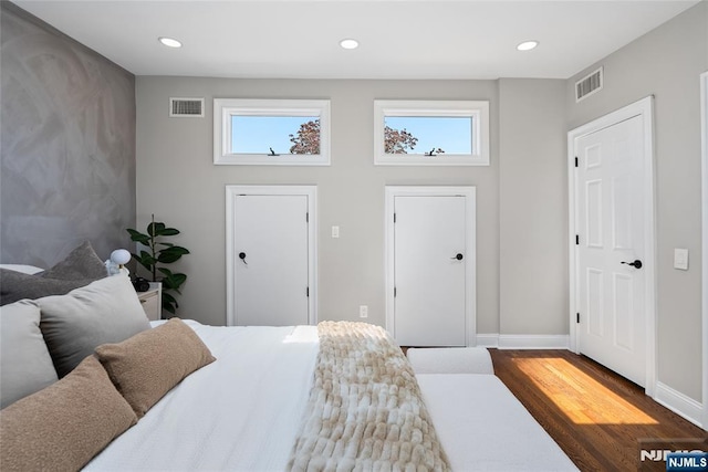 bedroom with wood finished floors, visible vents, and multiple windows