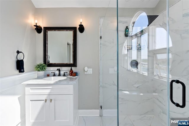 bathroom with a marble finish shower, baseboards, and vanity