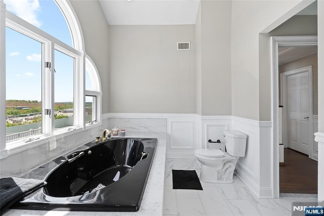 bathroom featuring marble finish floor, a wainscoted wall, and a wealth of natural light