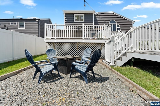 rear view of house with fence, stairs, a fire pit, and a deck