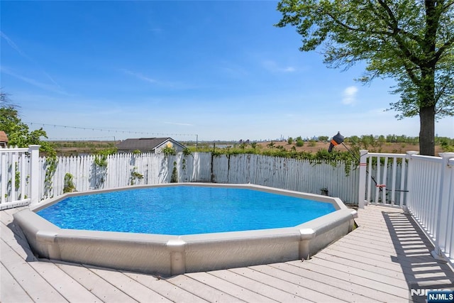 view of swimming pool featuring a fenced backyard, a wooden deck, and a fenced in pool