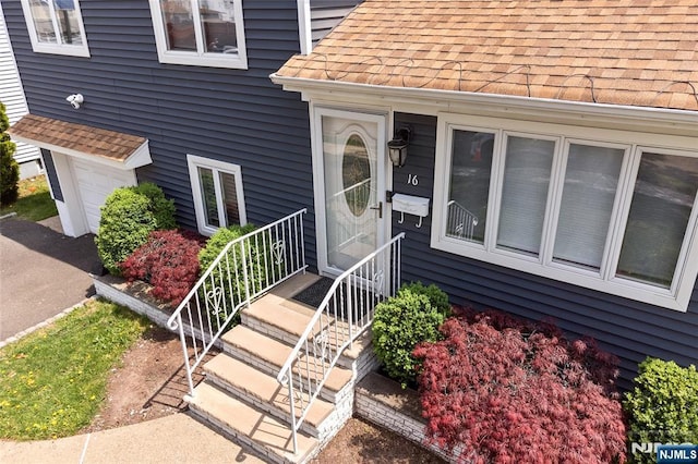 property entrance with roof with shingles and an attached garage