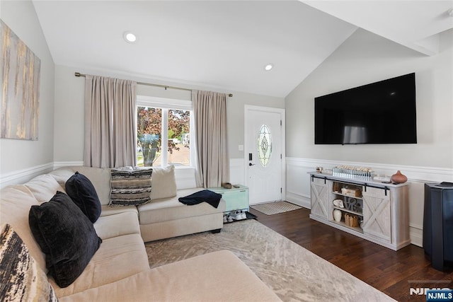 living area featuring a wealth of natural light, wood finished floors, a wainscoted wall, and vaulted ceiling