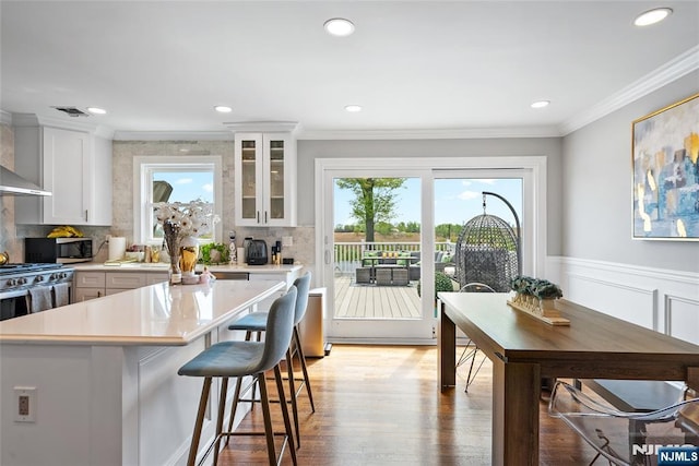 kitchen with white cabinets, glass insert cabinets, stainless steel microwave, and a healthy amount of sunlight