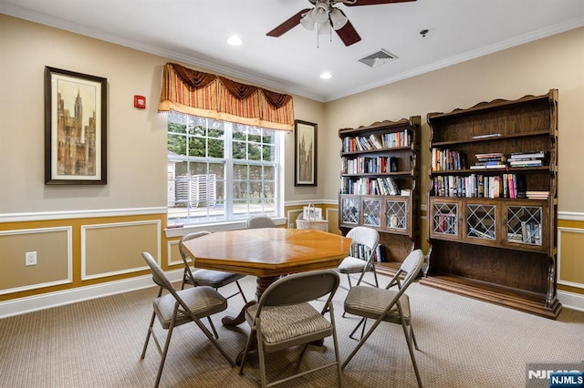 interior space featuring wainscoting, ornamental molding, a ceiling fan, and visible vents