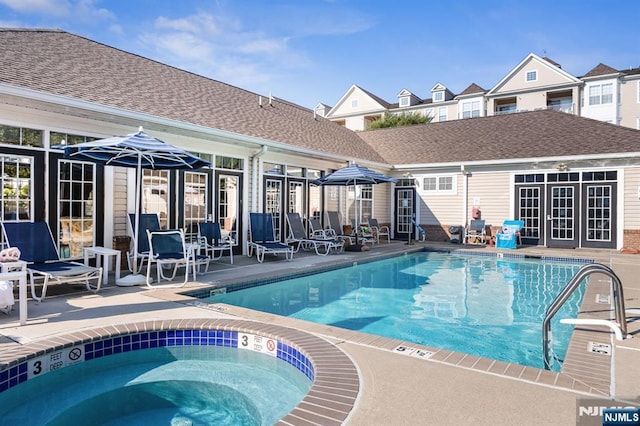 community pool with a hot tub, an outdoor structure, and a patio area