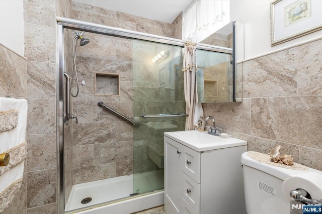 full bathroom featuring tile walls, a shower stall, vanity, and toilet