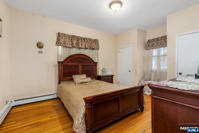 bedroom featuring light wood-style floors and baseboard heating