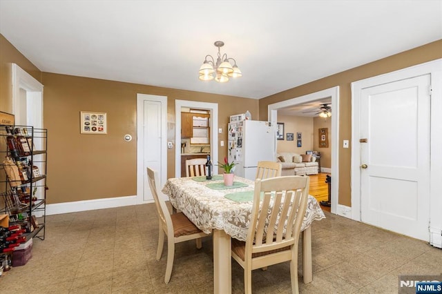 dining room featuring a chandelier, baseboards, ceiling fan, and light flooring