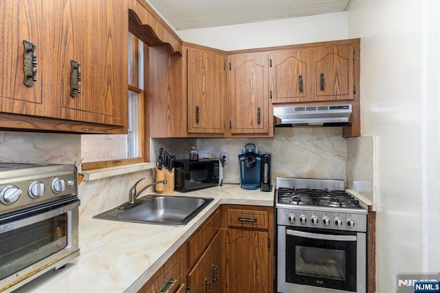 kitchen with gas stove, under cabinet range hood, black microwave, a sink, and light countertops