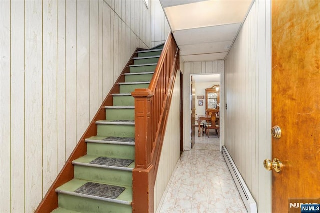 staircase with baseboard heating and wooden walls