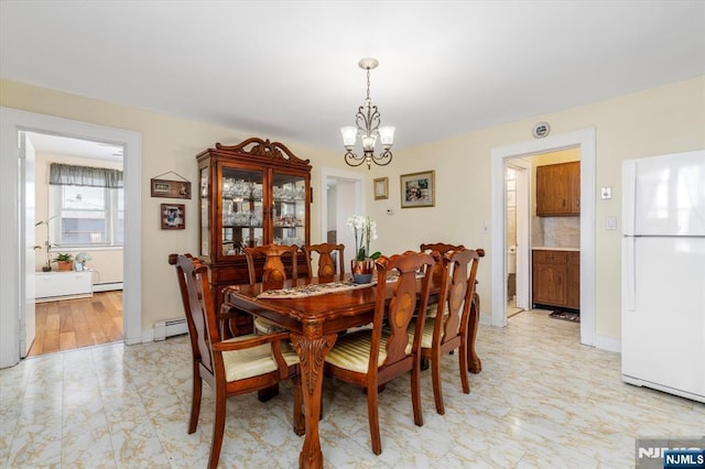 dining room with a chandelier, baseboard heating, and baseboards