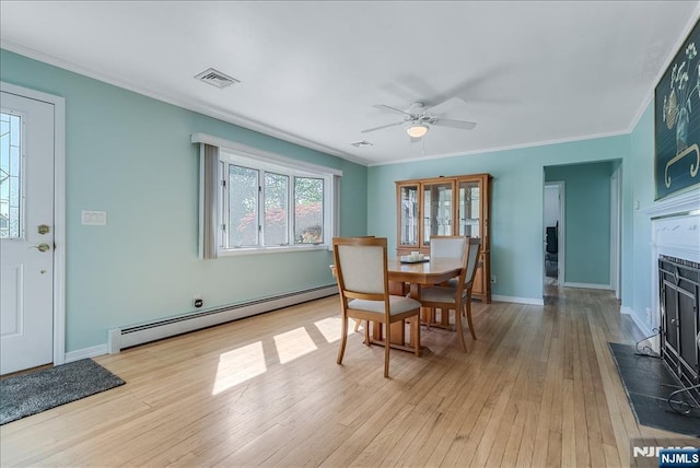 dining room featuring baseboard heating, light wood-style floors, crown molding, baseboards, and ceiling fan