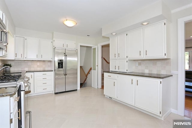 kitchen with dark stone counters, appliances with stainless steel finishes, decorative backsplash, and white cabinetry