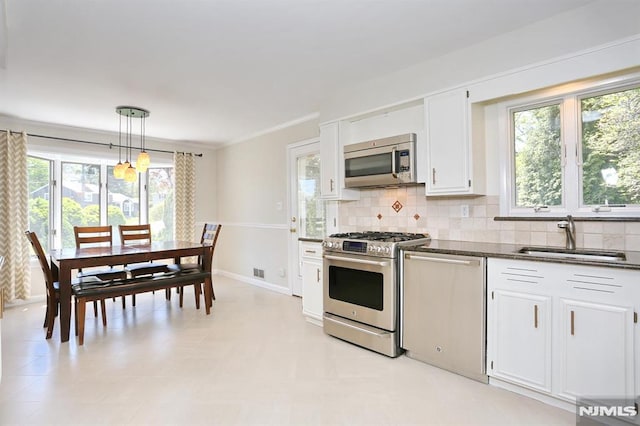 kitchen featuring backsplash, appliances with stainless steel finishes, white cabinetry, and a sink