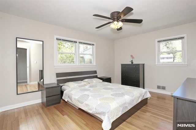bedroom with light wood finished floors, baseboards, a ceiling fan, and visible vents