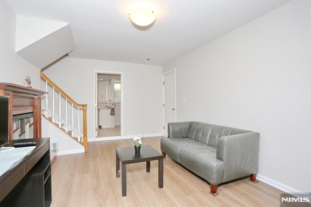 sitting room featuring stairway, light wood finished floors, and baseboards