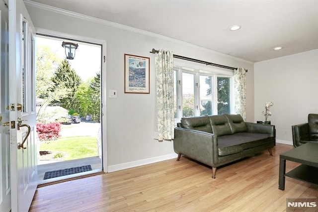 living room featuring light wood-style flooring, baseboards, and ornamental molding