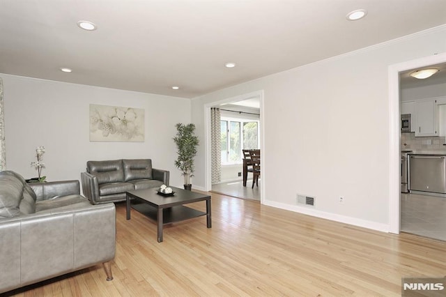 living room with visible vents, recessed lighting, light wood finished floors, crown molding, and baseboards