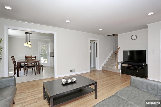 living room featuring crown molding, light wood-type flooring, stairway, visible vents, and recessed lighting