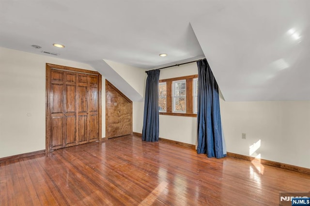 bonus room with baseboards, visible vents, and wood finished floors